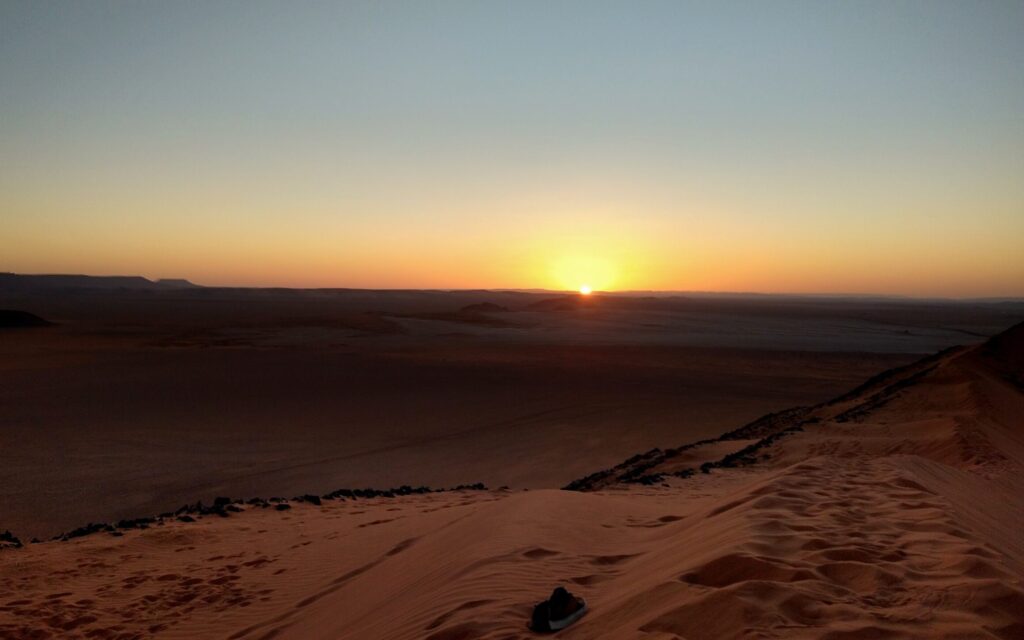 up on the sand dune looking across the plain into the sunset